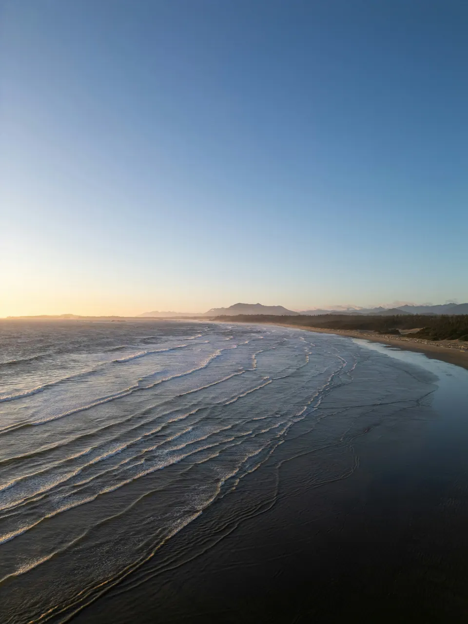 Ocean waves following the shoreline at Long Beach in Tofino, British Columbia