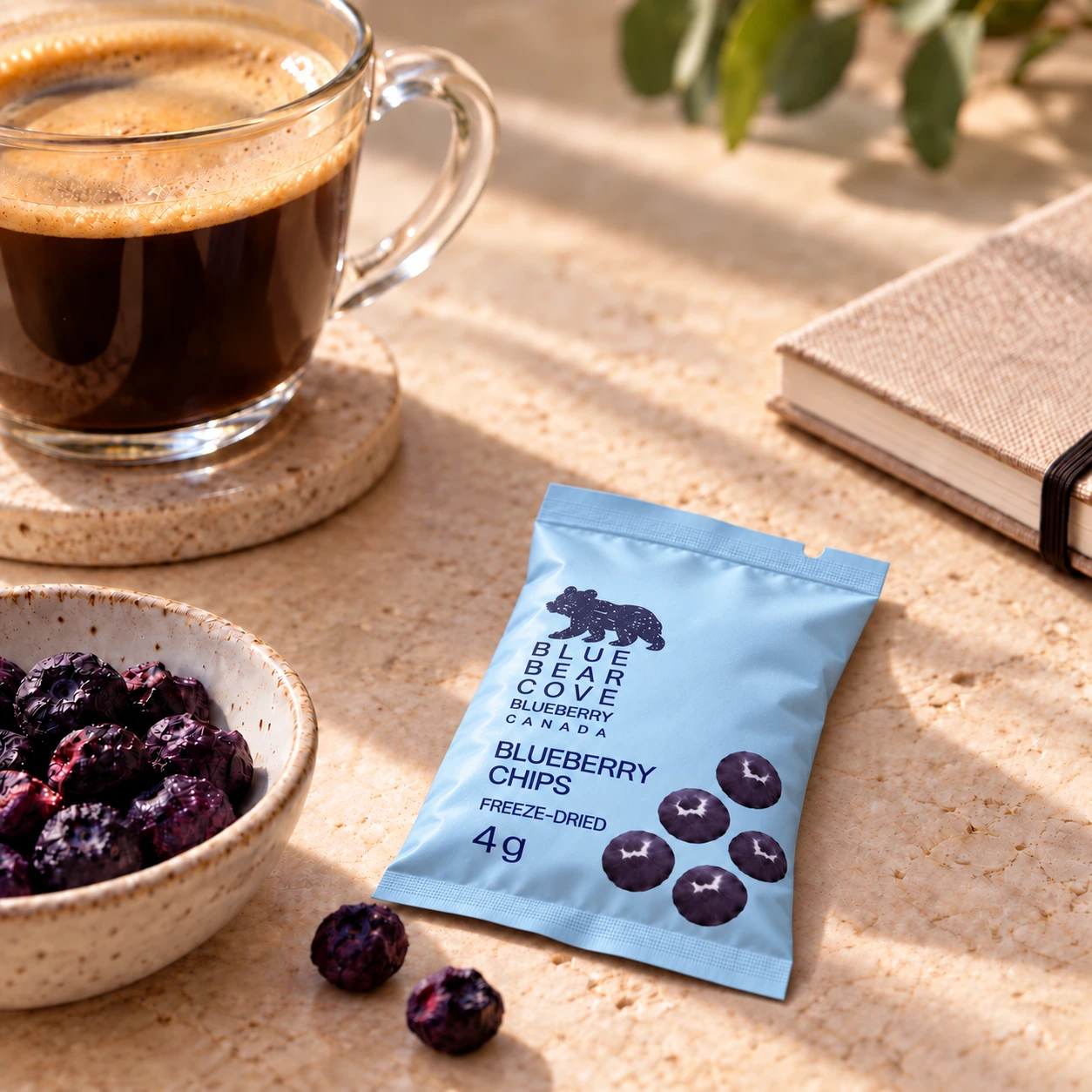 A blueberry chip sachet beside a glass coffee cup and whole freeze-dried blueberries.