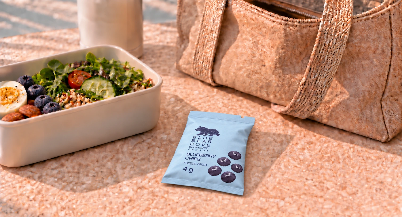 A blueberry chip sachet beside a lunch container and bag.